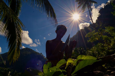 Low angle view of woman standing by trees against sky