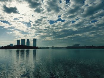 Scenic view of lake by buildings against sky during sunset