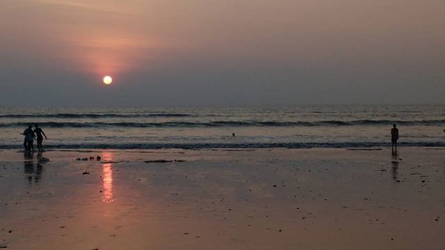 sea, horizon over water, water, beach, leisure activity, shore, lifestyles, sunset, silhouette, sky, scenics, men, vacations, beauty in nature, reflection, tranquil scene, full length, wave