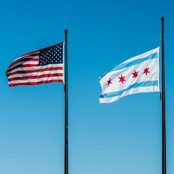 Low angle view of flag against clear blue sky