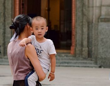 Mother and son standing on footpath