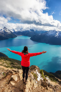 Full length rear view of man standing on rock against mountains
