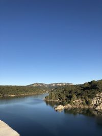 Scenic view of lake and mountains against clear blue sky