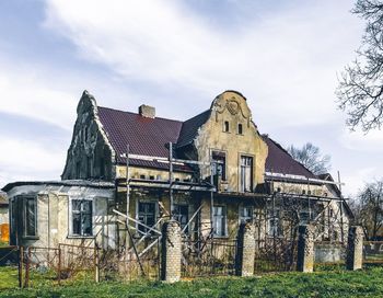 Exterior of old house on field against sky