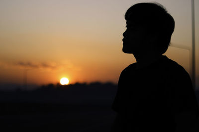 Silhouette man looking at sunset sky