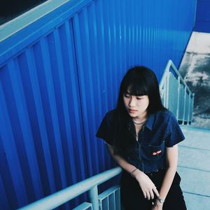 Young woman standing against blue wall