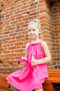 Portrait of girl standing against brick wall