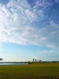 Scenic view of grassy field against cloudy sky