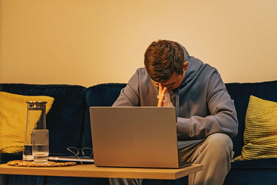 Frustrated man sitting on the sofa in front of his laptop. sad, alone, solving a problem