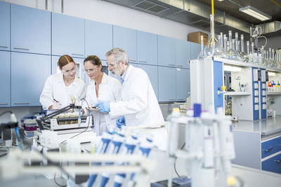 Three scientists in lab examining samples