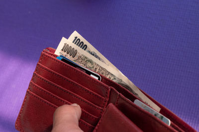 Close-up of hand holding paper against blue wall