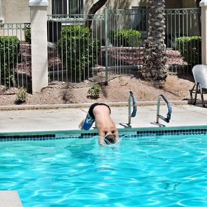 Low section of man jumping in swimming pool