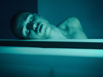 Close-up of shirtless young man sleeping in bathtub at home