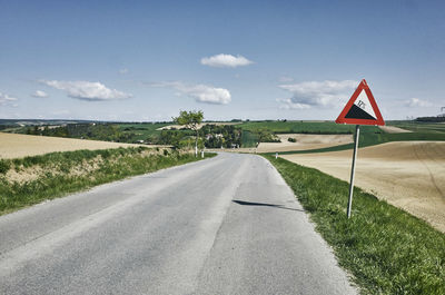 Road amidst field against sky