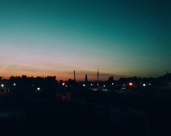 Silhouette of factory against sky at night