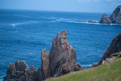 Rock formation on sea shore against sky