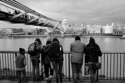 Rear view of people walking on bridge over river