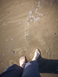 Low section of person legs on sand at beach