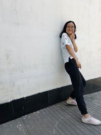 Young woman standing against wall