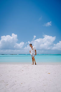 Man standing on beach against blue sky
