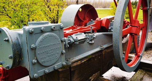 Close-up of red and gray machinery against trees