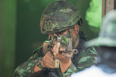 View of soldier holding rifle standing outdoors