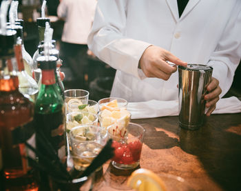 Midsection of man preparing food in glass on table