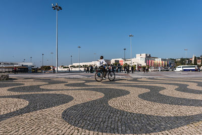 People riding bicycle on road against blue sky