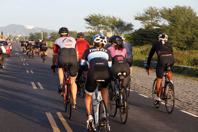 Rear view of people riding bicycle on road