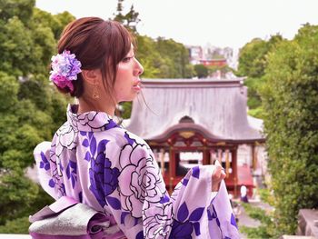 Young woman with purple flowers against plants