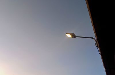 Low angle view of illuminated street light against sky