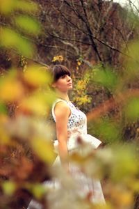 Side view of young woman standing amidst plants