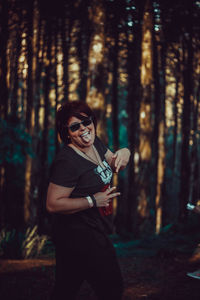 Portrait of young man wearing sunglasses standing in forest