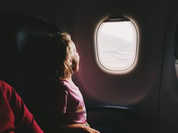 Rear view of woman looking through airplane window
