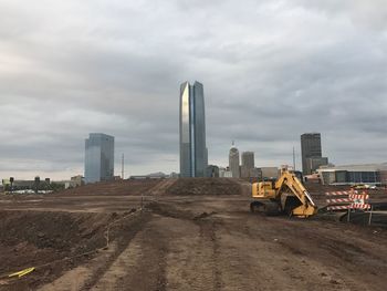 Construction site by buildings against sky in city