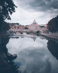 Arch bridge over river against cloudy sky