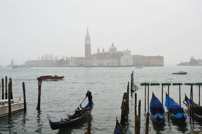 Boats moored in sea with city in background