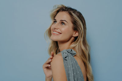 Portrait of young woman standing against blue background