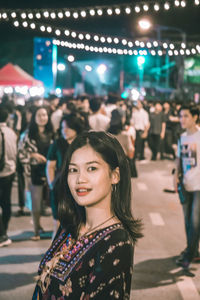 Portrait of woman standing in illuminated city at night