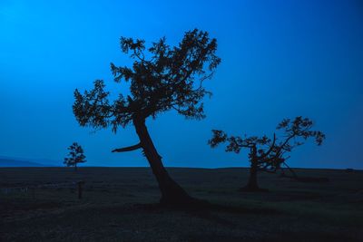 Silhouette tree on field against clear blue sky