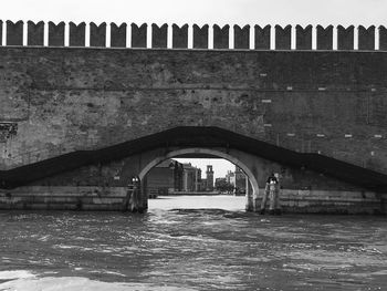 Arch bridge over river against buildings