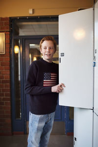 High school boy standing by locker