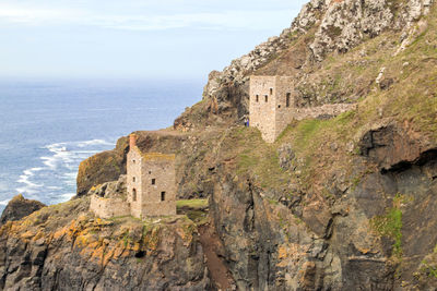 Castle on cliff by sea against sky