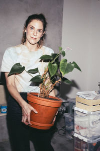 Portrait of woman holding potted plant during relocation of house