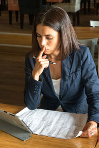 Young woman looking down while sitting on table