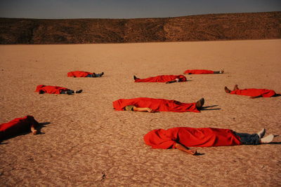  people covered in red fabric lying on land