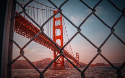 Chainlink fence against golden gate bridge against sky