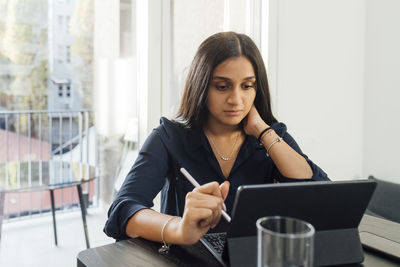 Woman studying through tablet pc on table at home