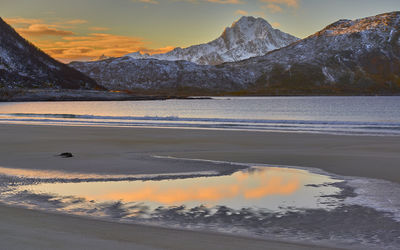 Scenic view of lake by mountains against sky during sunset