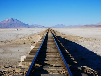 Scenic view of railroad track in desert against clear blue sky